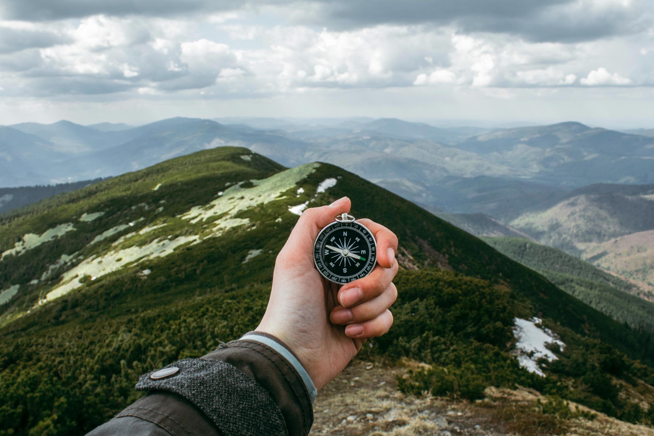 person holding a compass in the mountains